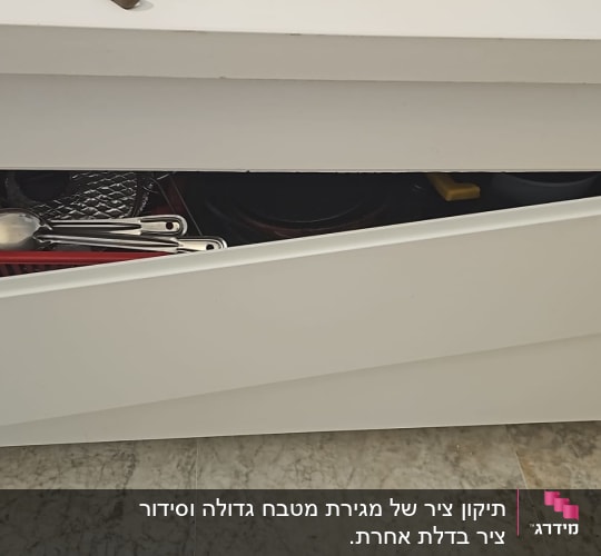 מגירה פתוחה עם כלי מטבח בתוכה
